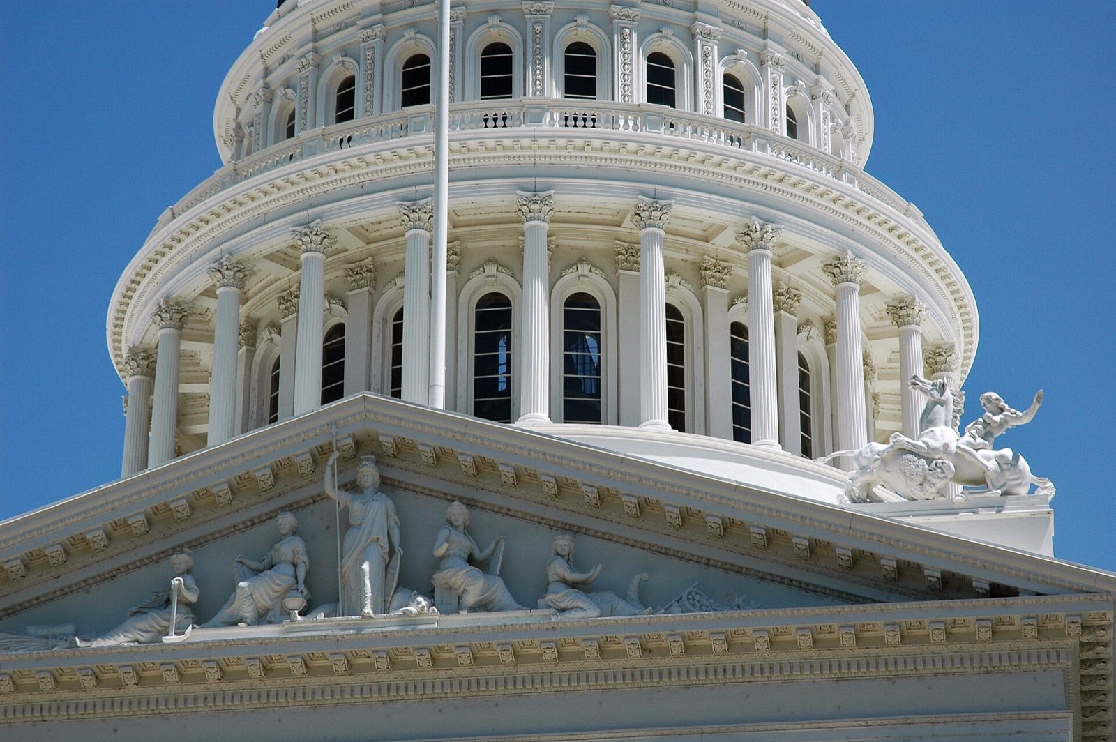 The dome and sculpted pediment of the California State Capitol in Sacramento against a blue sky